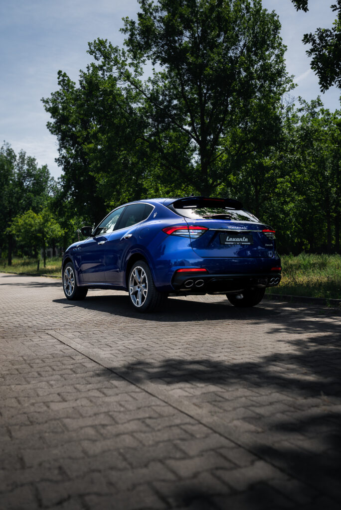 Das hochformatige Bild zeigt den blauen Maserati Levante, ein SUV-Modell des italienischen Automobilherstellers, seitlich von hinten mit leuchtenden LED-Heckscheinwerfern. Fotografiert für das Maserati-Autohaus Geisser in Karlsruhe.