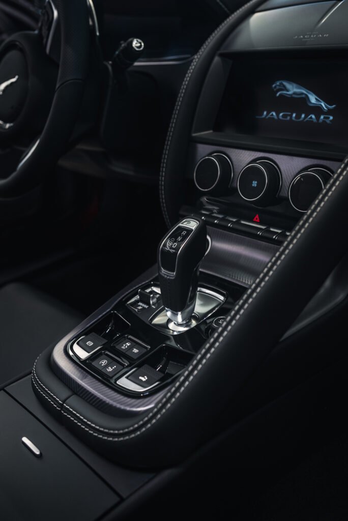 Detailfotografie vom Fahrzeug-Interieur eines Jaguar F-Type Sportwagens mit LCD-Bildschirm und Schaltung.