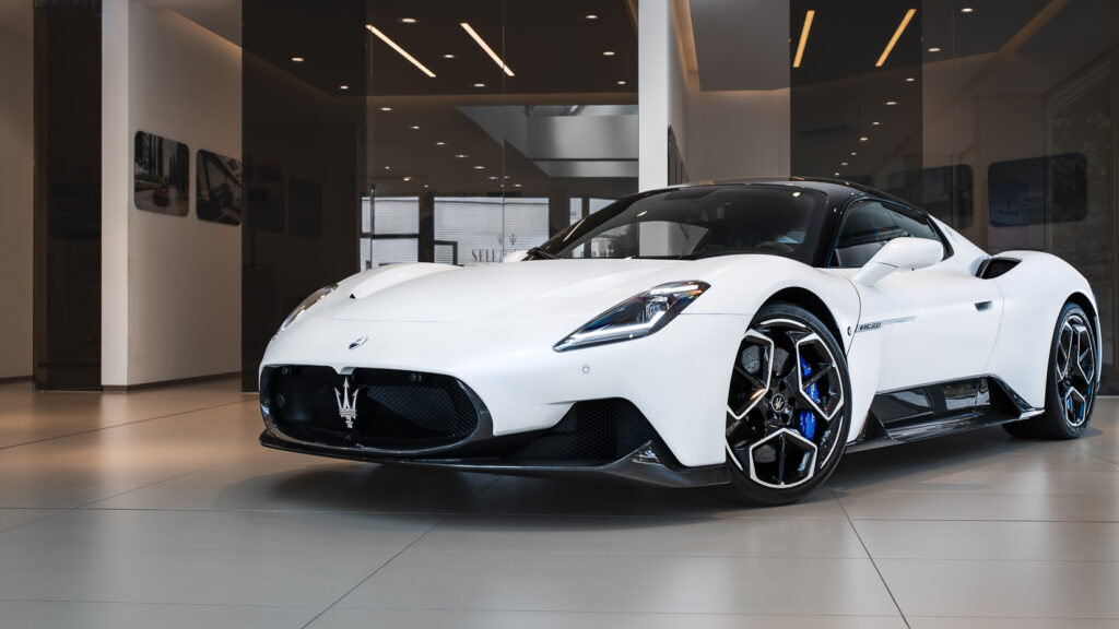 Das Bild zeigt den weißen MC20, ein Supersportwagen des italienschen Herstellers Maserati, in der Dreiviertelansicht. Der Fokus liegt auf dem Scheinwerfer und dem blauen Bremssattel.